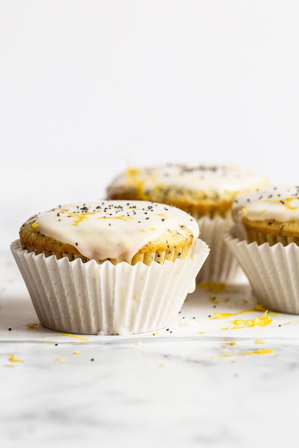 3 glazed lemon poppyseed muffins on a marble counter