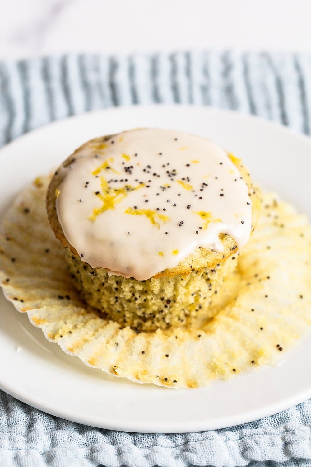 glazed lemon poppyseed muffin on a plate with the wrapper being removed