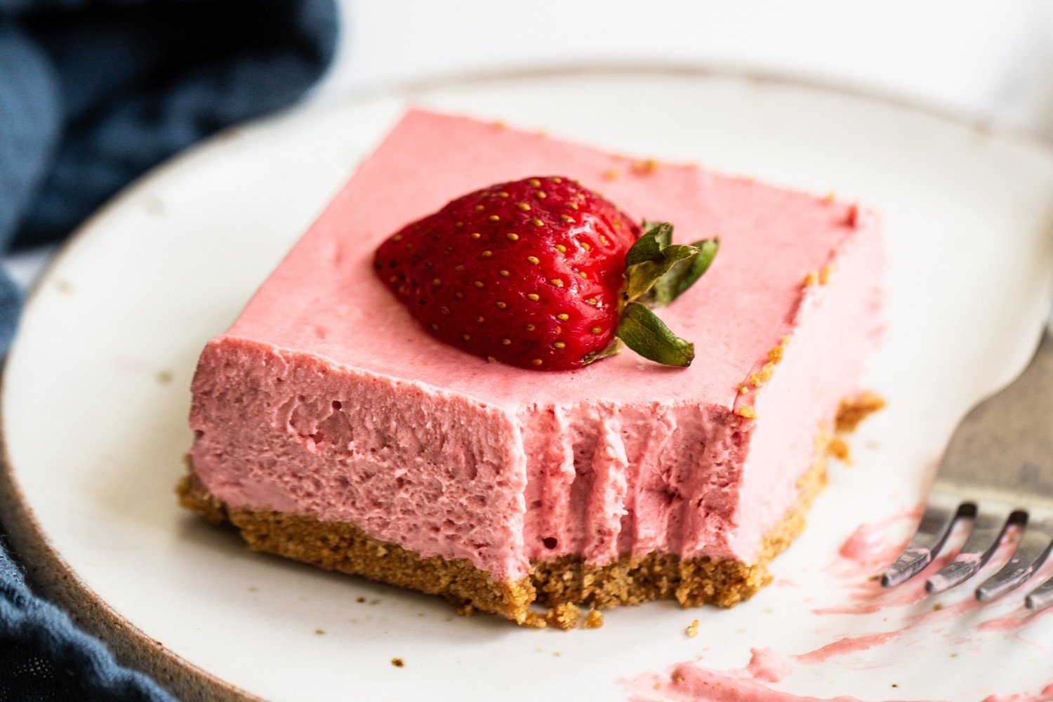 a slice of cheesecake with a strawberry on top, ready to serve.