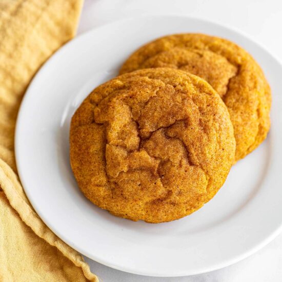 homemade pumpkin snickerdoodle cookies on a plate with a yellow towel