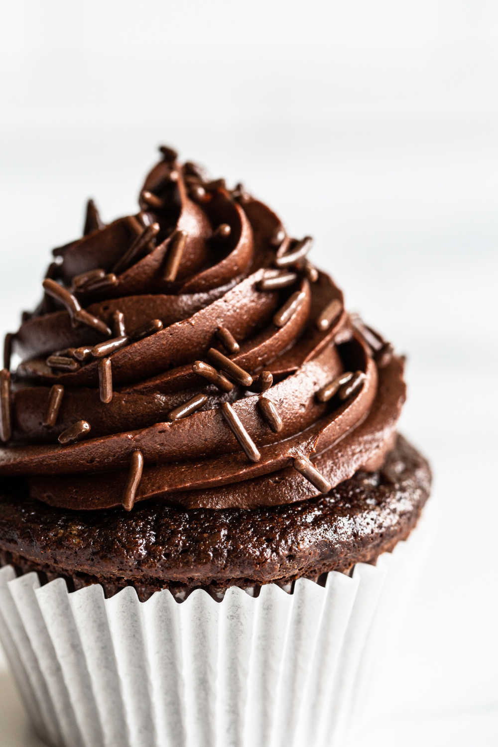 close up of chocolate frosting and chocolate sprinkles on a chocolate cupcake