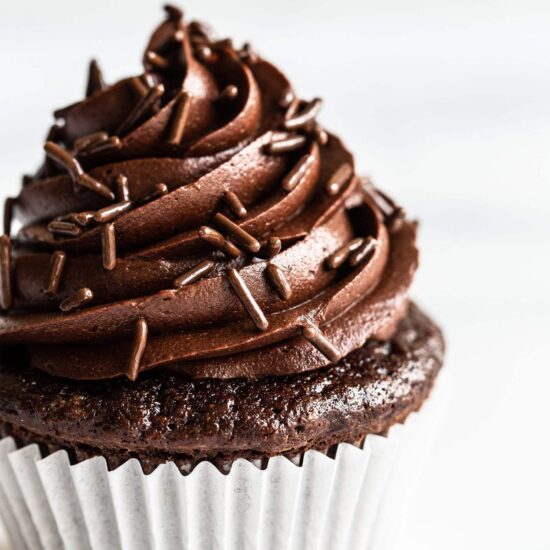 chocolate buttercream on top of a chocolate cupcake with chocolate sprinkles