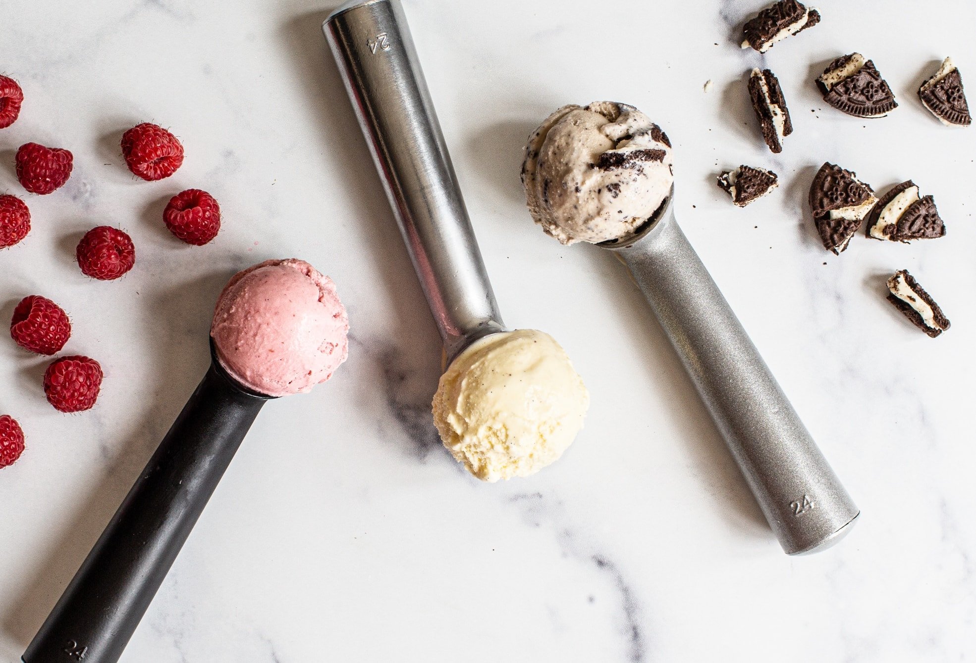 three ice cream scoops of fresh homemade ice cream - one strawberry, one vanilla and one cookies and cream