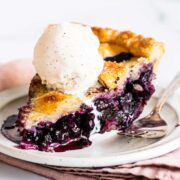 slice of homemade blueberry pie and a scoop of vanilla ice cream on top