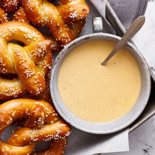 a bowl of beer cheese dip surrounded by homemade Bavarian-style soft pretzels.