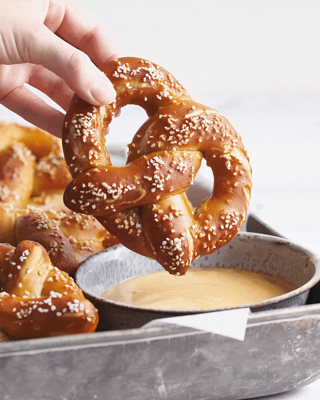 homemade pretzel being dunked into beer cheese dip