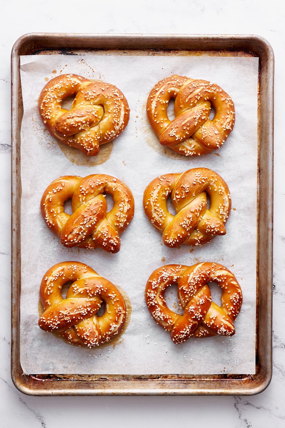 homemade pretzels on a baking sheet after being salted