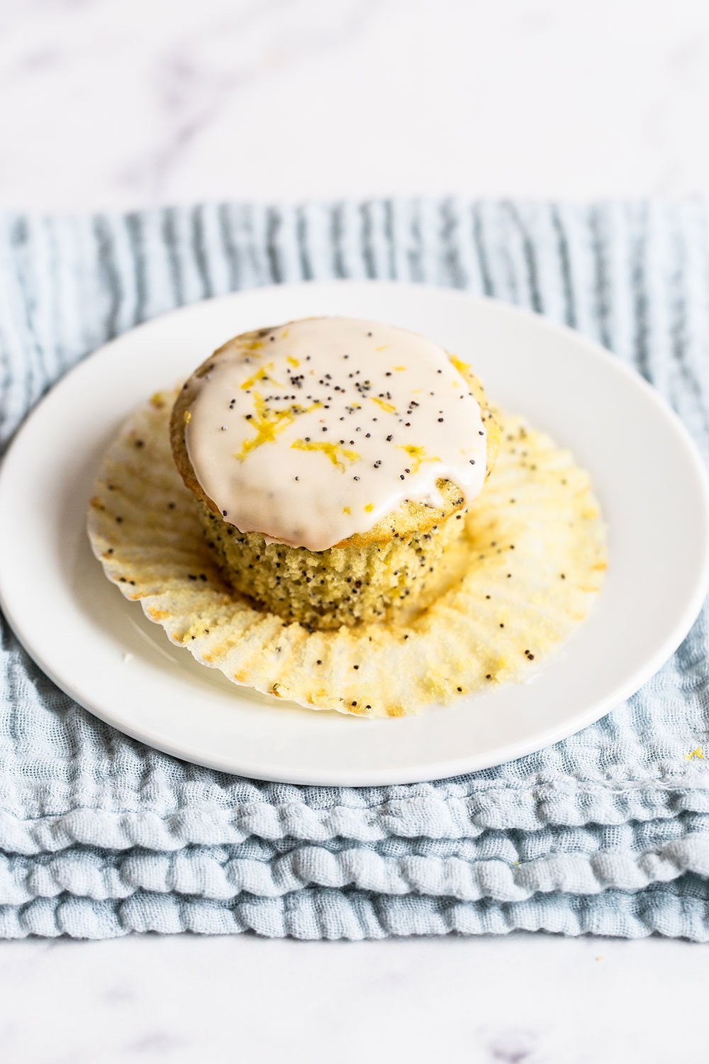 glazed lemon poppyseed muffin on a plate with the wrapper removed