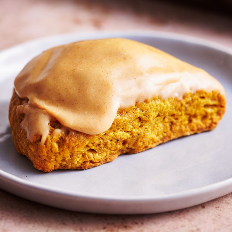 homemade pumpkin scones with pumpkin spice glaze on a plate