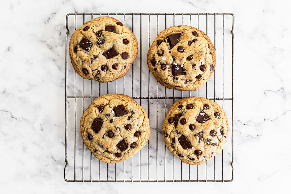 four giant chocolate chip cookies sitting on a wire cooling rack