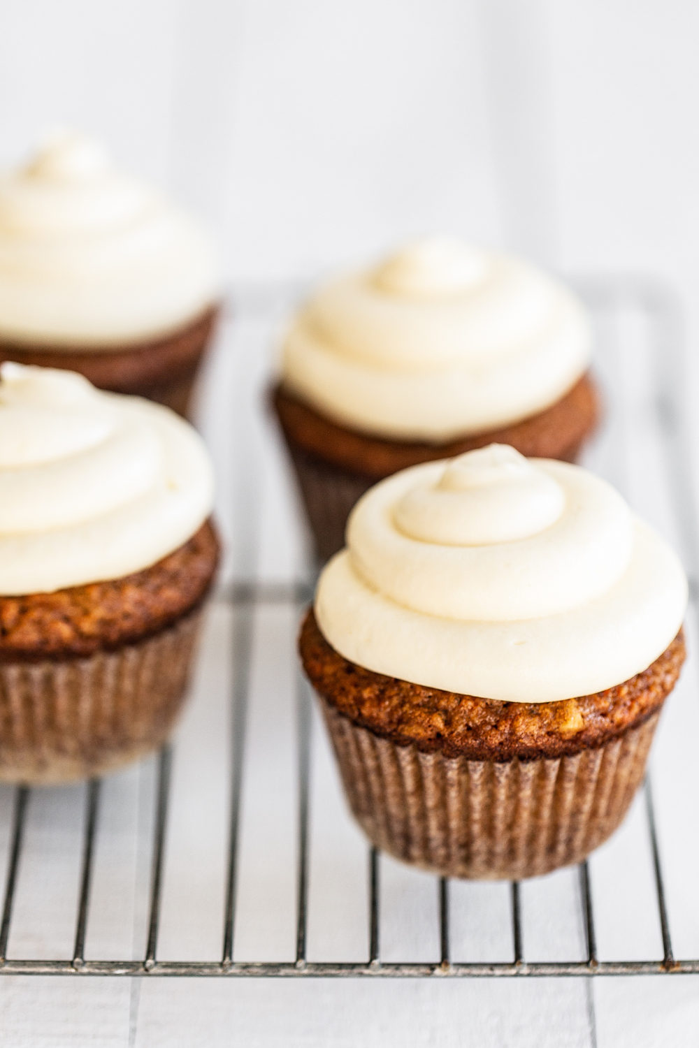 Carrot Cake Cupcakes with cream cheese frosting on a wire rack.
