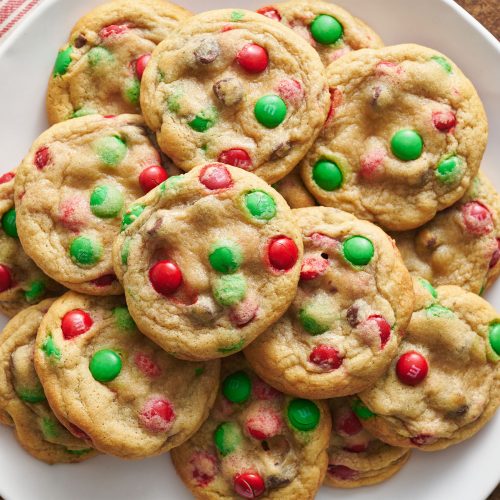 a pile of M&M Christmas Cookies on a plate.