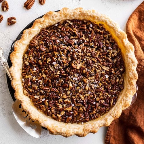 a whole pecan pie from the top, unsliced and still in its glass pie pan.