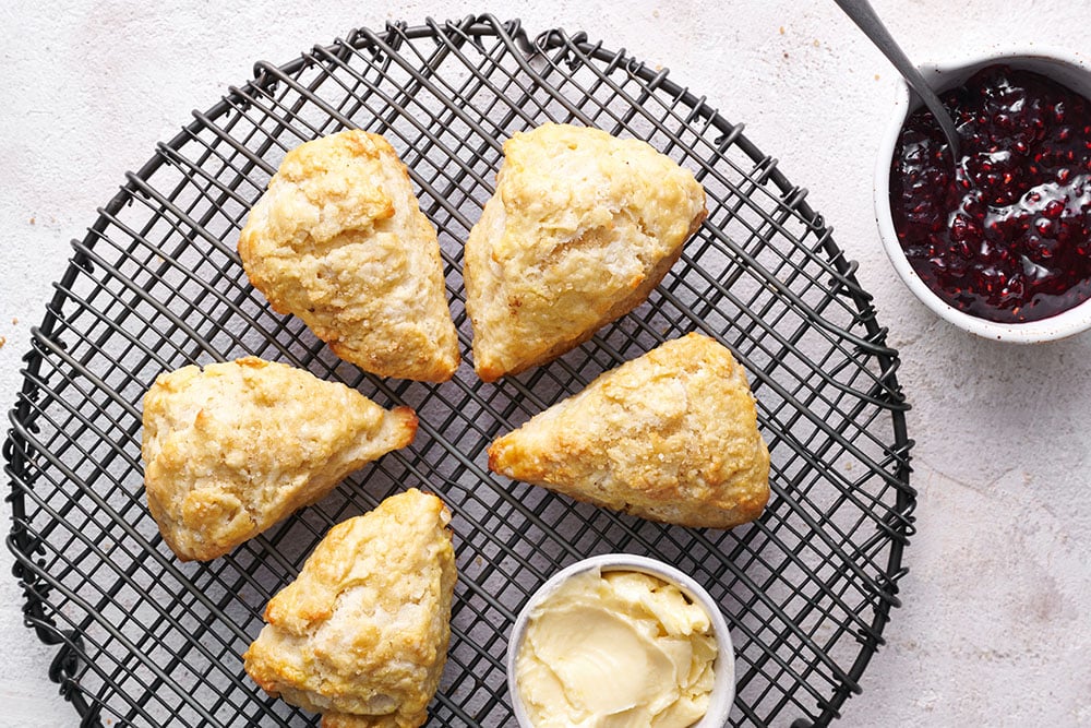 scones on a wire tray with a small pot of butter next to them