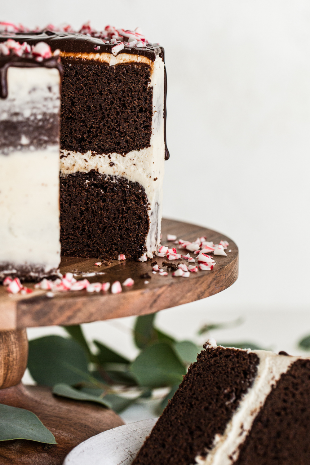 the full decorated Peppermint Chocolate Cake on a cake stand, with a slice taken out.