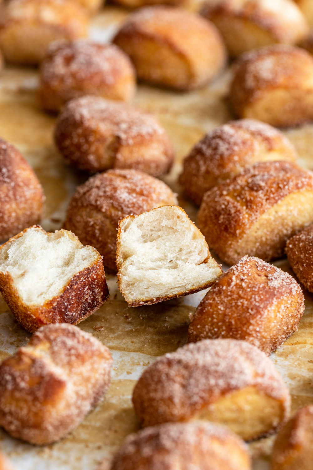 pretzel bites coated in cinnamon sugar on a baking tray, with one broken open so you can see the texture