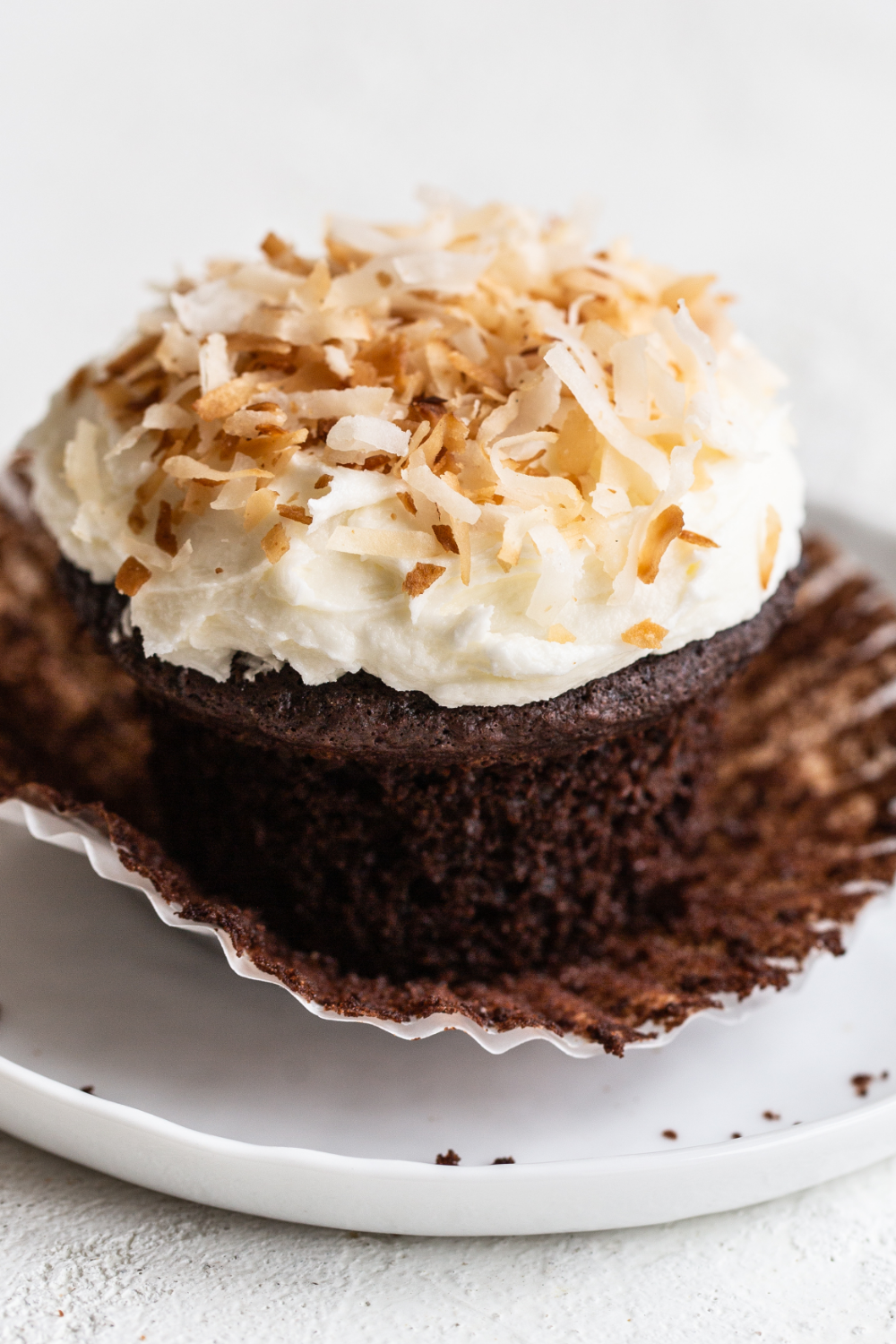 chocolate coconut cupcake with its wrapper being taken off.