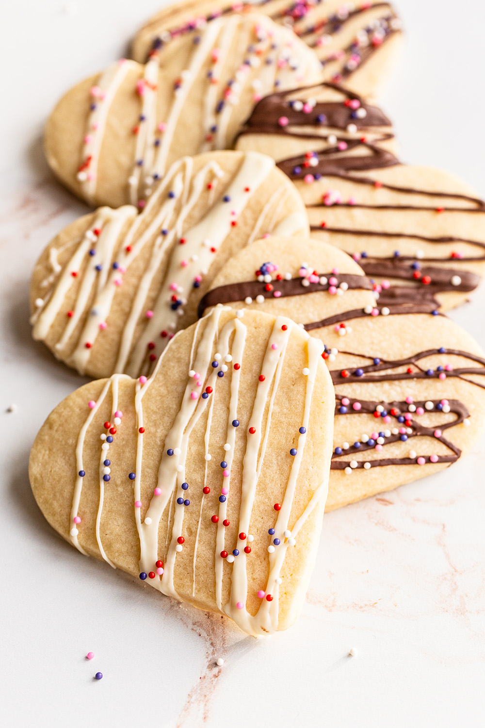 a few sugar cookies neatly stacked, all drizzled with chocolate and sprinkles on top.