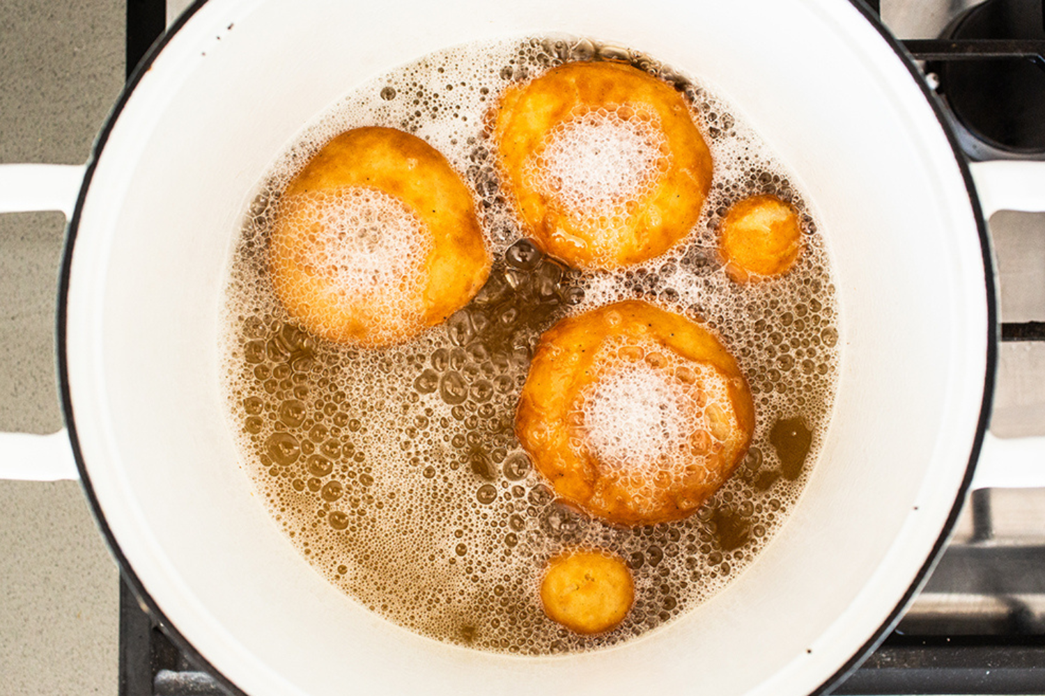 three donuts in oil frying.