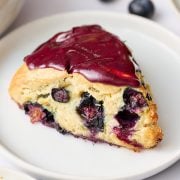 homemade blueberry scone on a plate with a blueberry lemon glaze on top