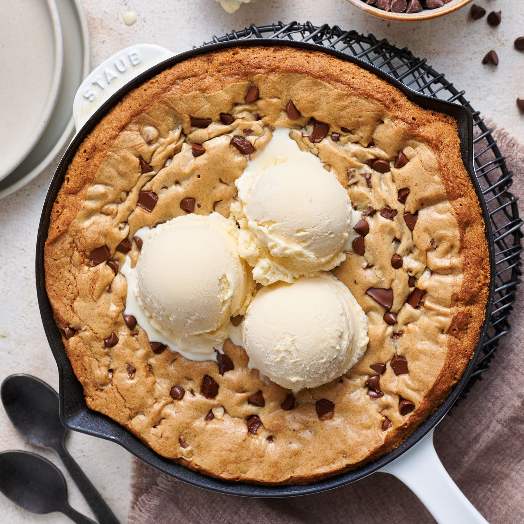 chocolate chip skillet cookie in a cast iron skillet with scoops of vanilla ice cream on top