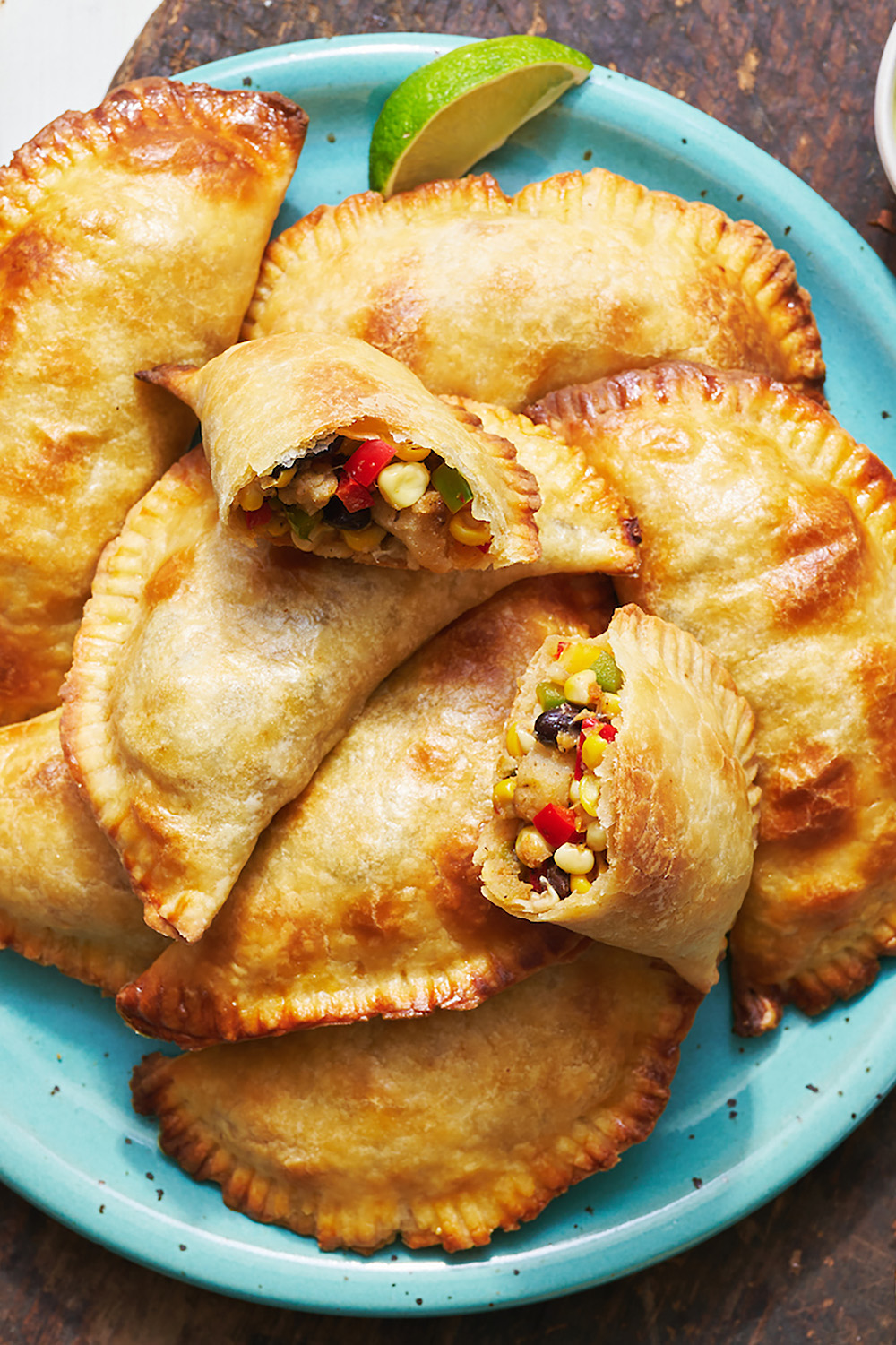 vegetable empanadas on a plate with one empanada cut open to see veggie black bean and corn filling