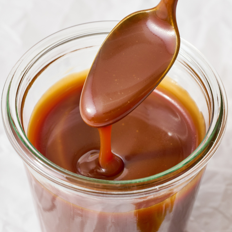 a big spoonful of caramel drizzling back into the glass jar beneath it.