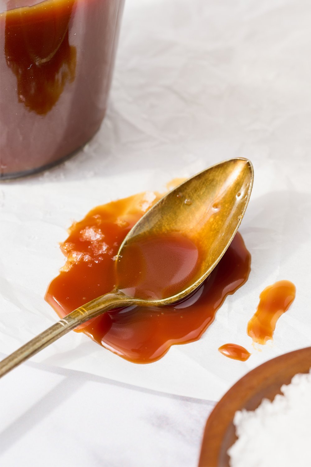 a spoon with some leftover caramel on it, resting in a small pool of caramel.
