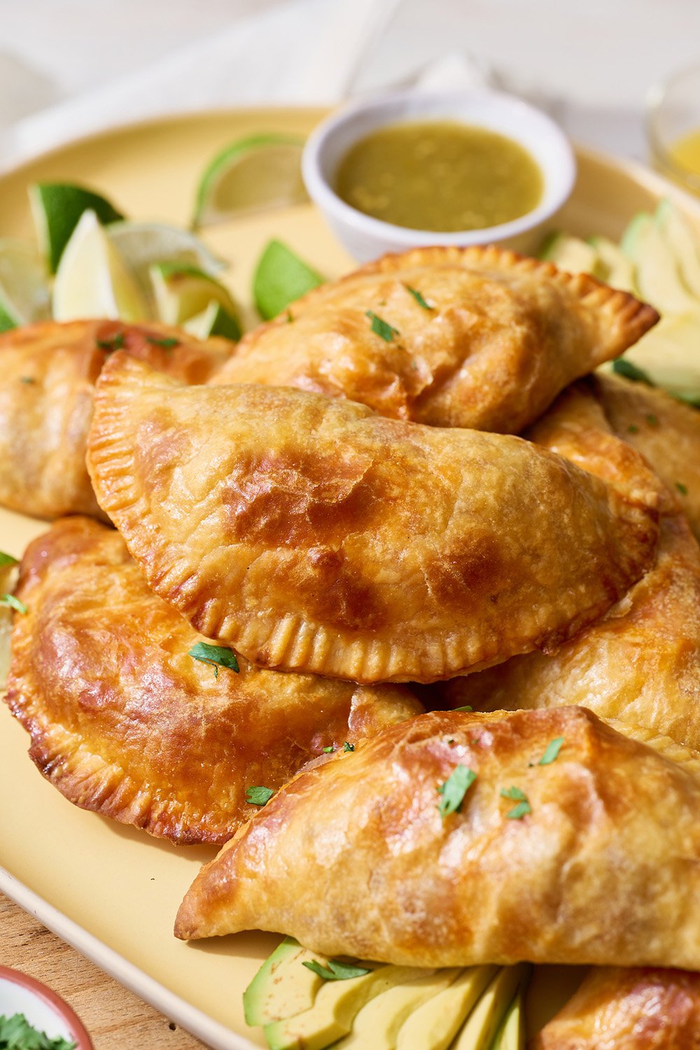 a small pile of Breakfast Empanadas with a small bowl of dipping sauce behind.