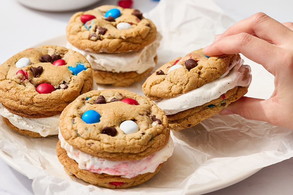 four 4th of July ice cream sandwiches, with Tessa's hand reaching in to grab one!