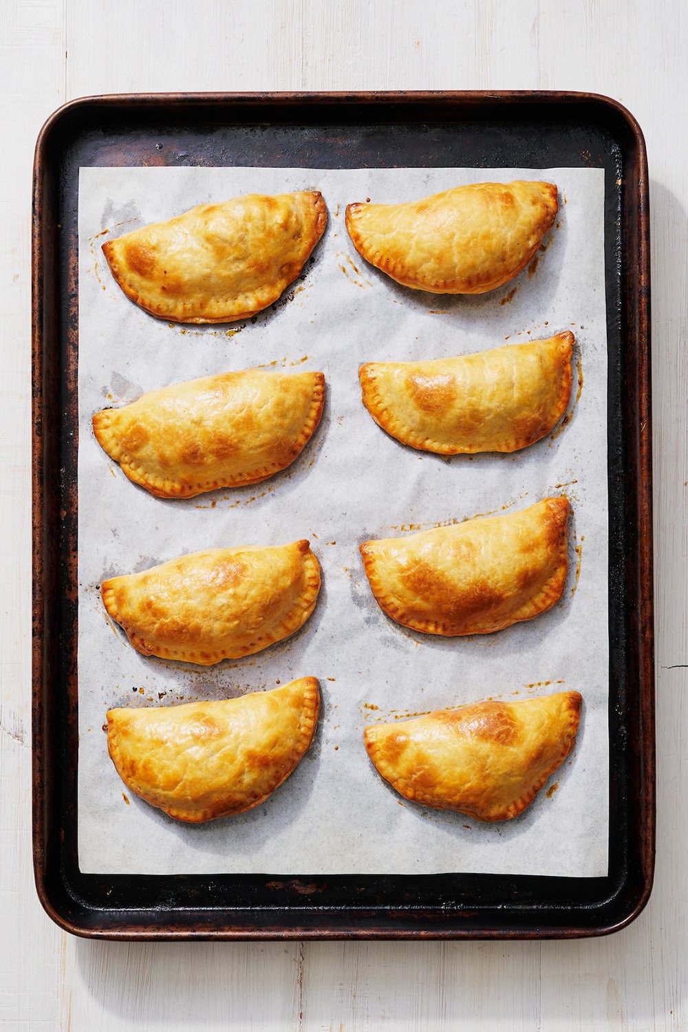 baked empanadas on a rimmed baking sheet, fresh out of the oven
