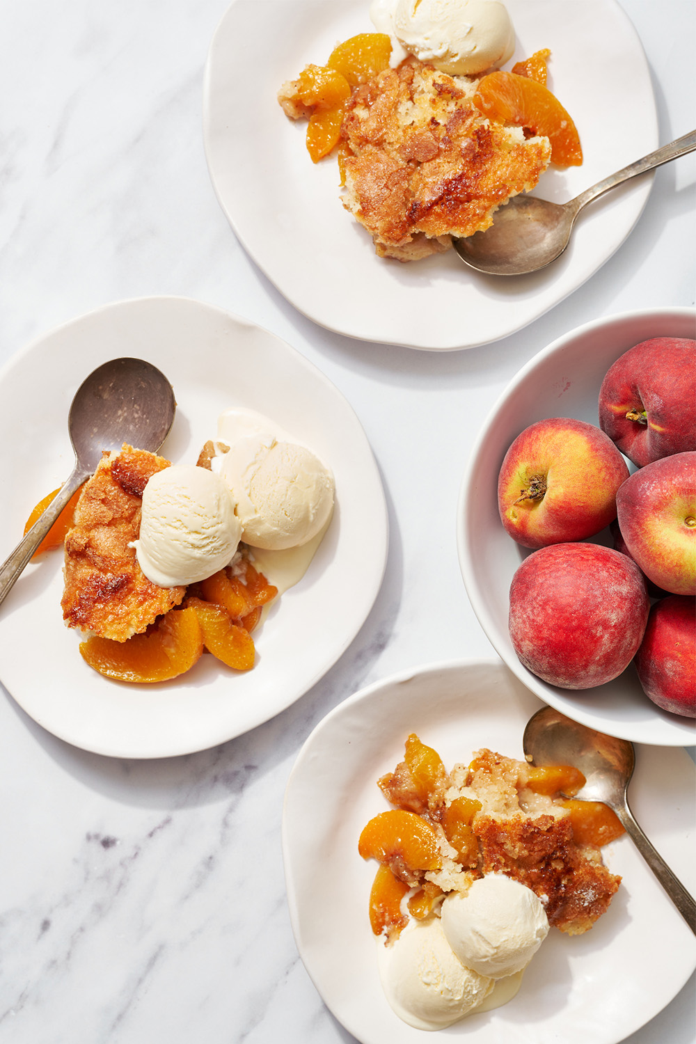 plates of brown butter peach cobbler being served with vanilla ice cream