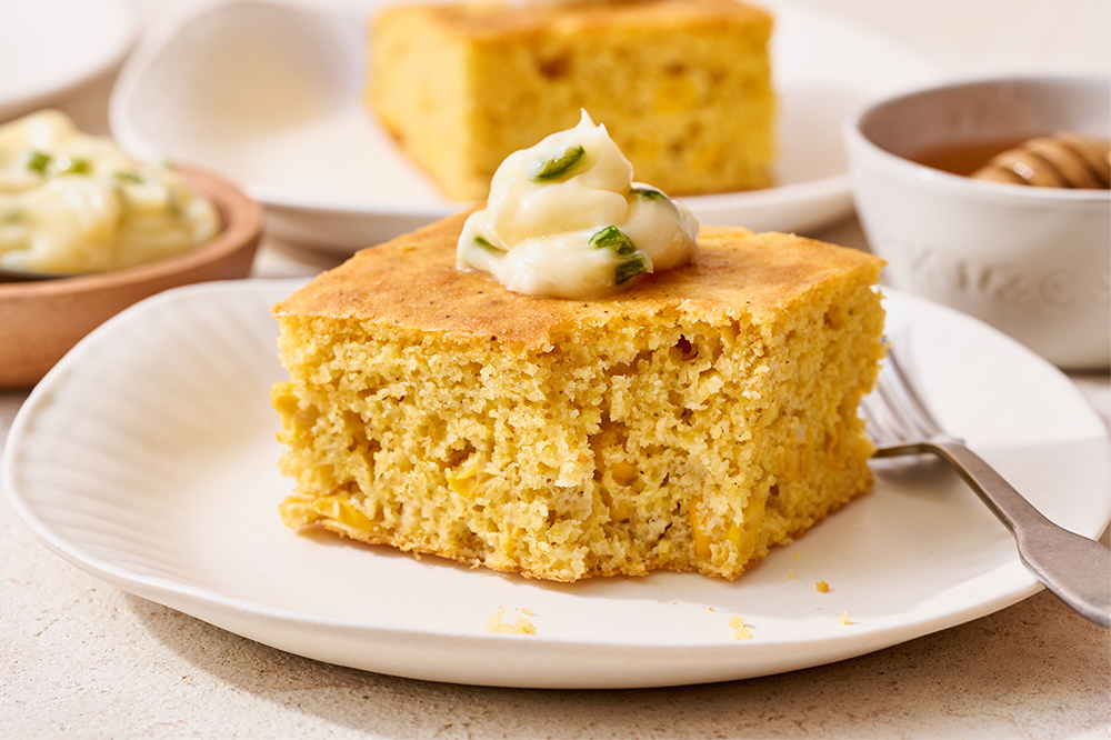 slice of cornbread on a plate with jalapeno butter piped on top, ready to serve