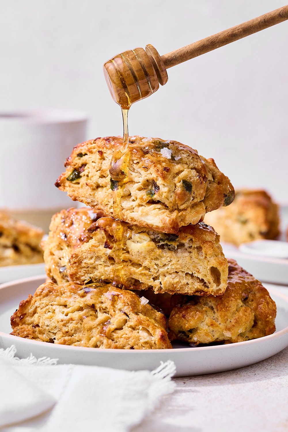 honey being drizzled on a stack of savory scones.