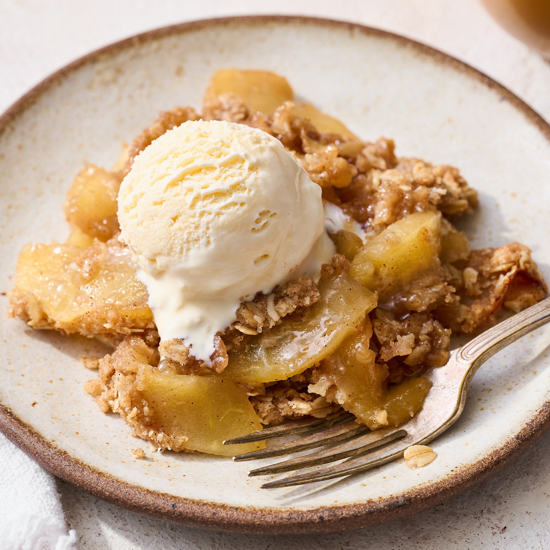 homemade apple crisp with streusel topping on a plate with a scoop of vanilla ice cream on top