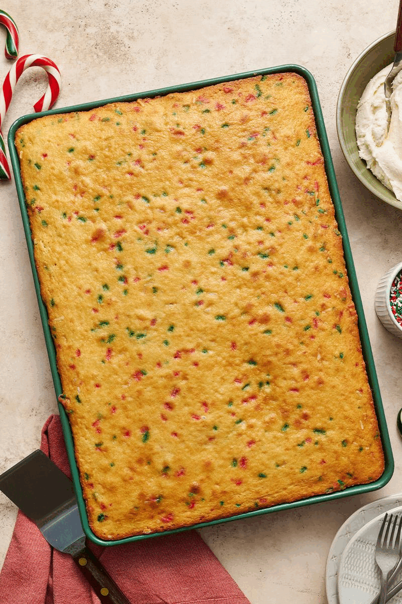 gif showing the christmas funfetti sheet cake in its pan, baked, then frosted, then topped with holiday sprinkles.
