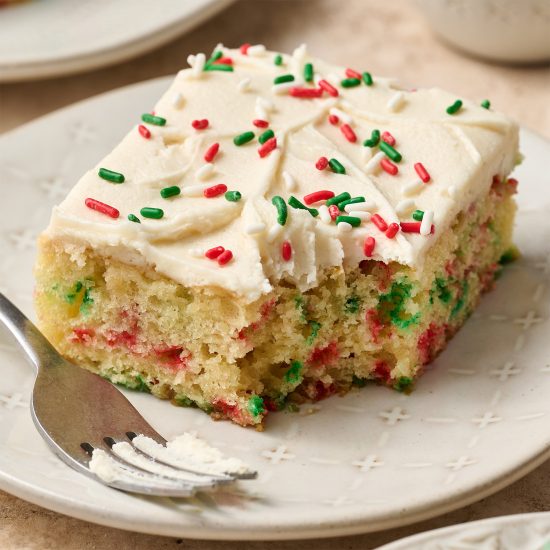 slice of christmas sheet cake on a plate with a bite taken out