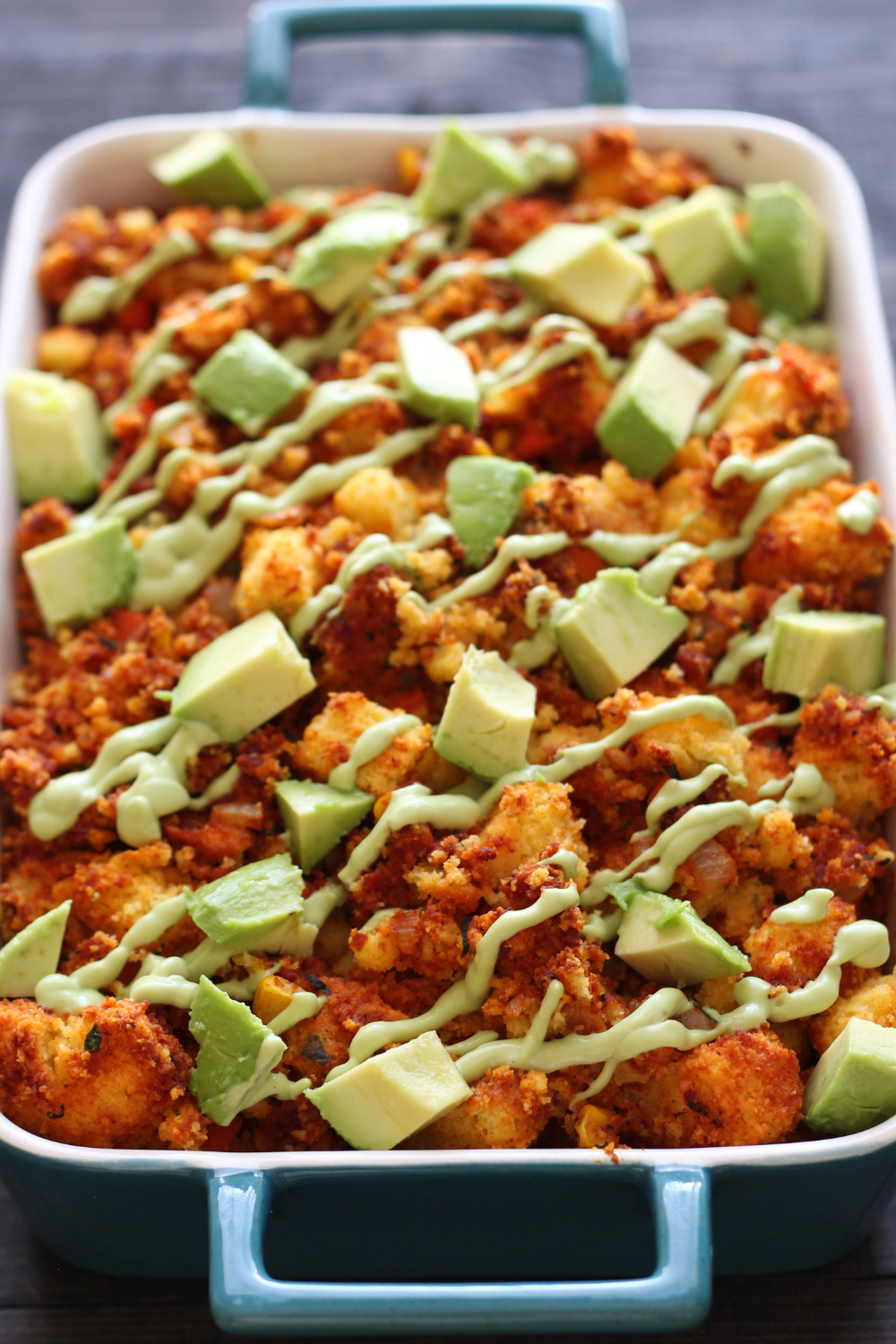 the Southwest Cornbread Chorizo Stuffing with Avocado in a pan, drizzled with avocado creama, ready to serve.