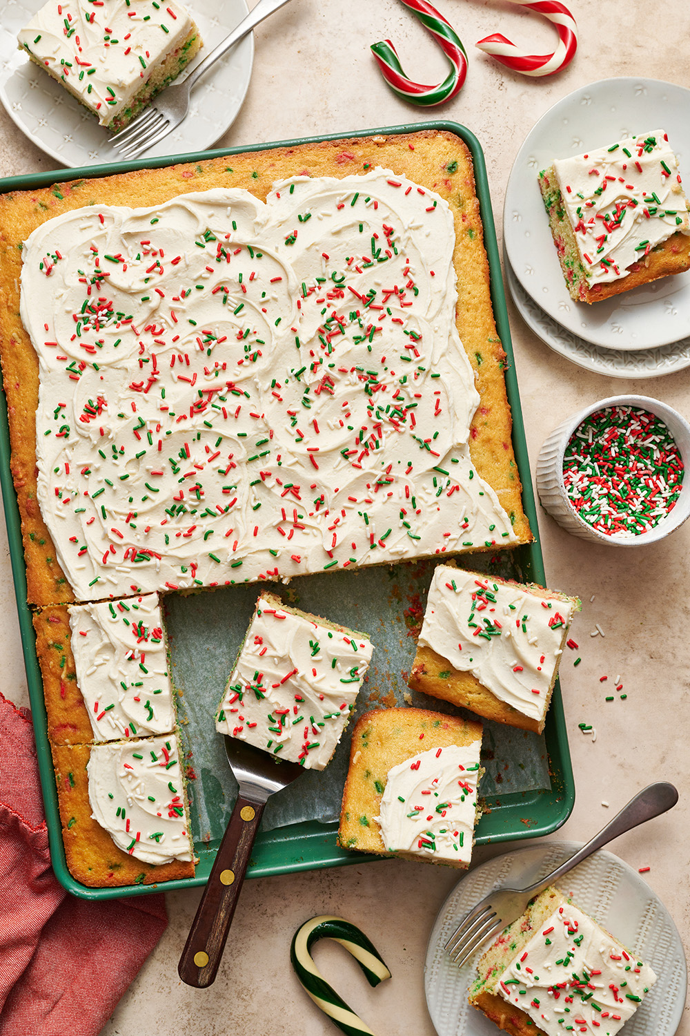 the christmas funfetti sheet cake in its pan, with slices being removed ready to serve.