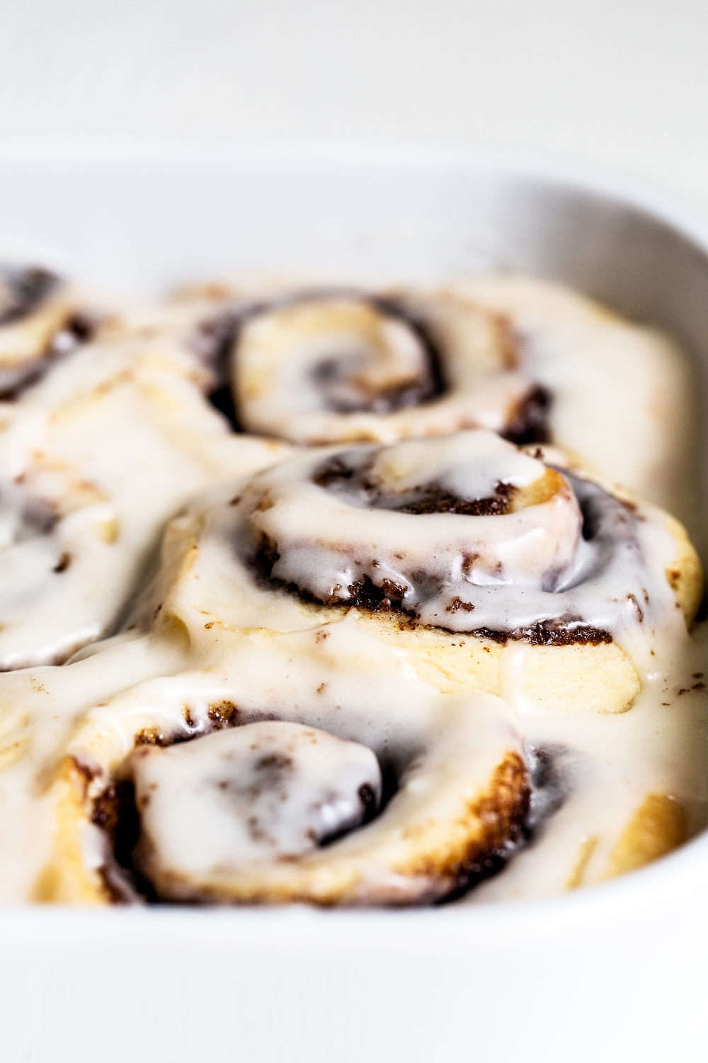 gooey cinnamon rolls in their baking pan, covered in white icing, ready for serving.