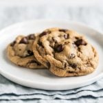two soft chocolate chip cookies on a white plate.