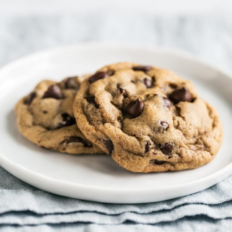 two soft chocolate chip cookies on a white plate.