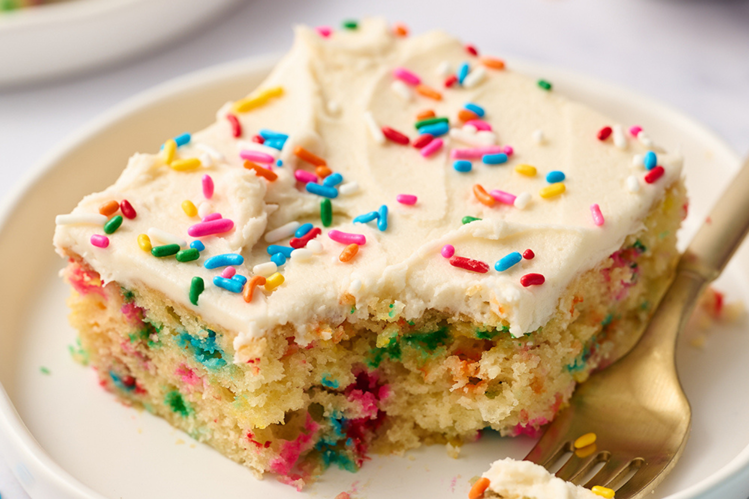 a slice of funfetti cake with a bite taken out.