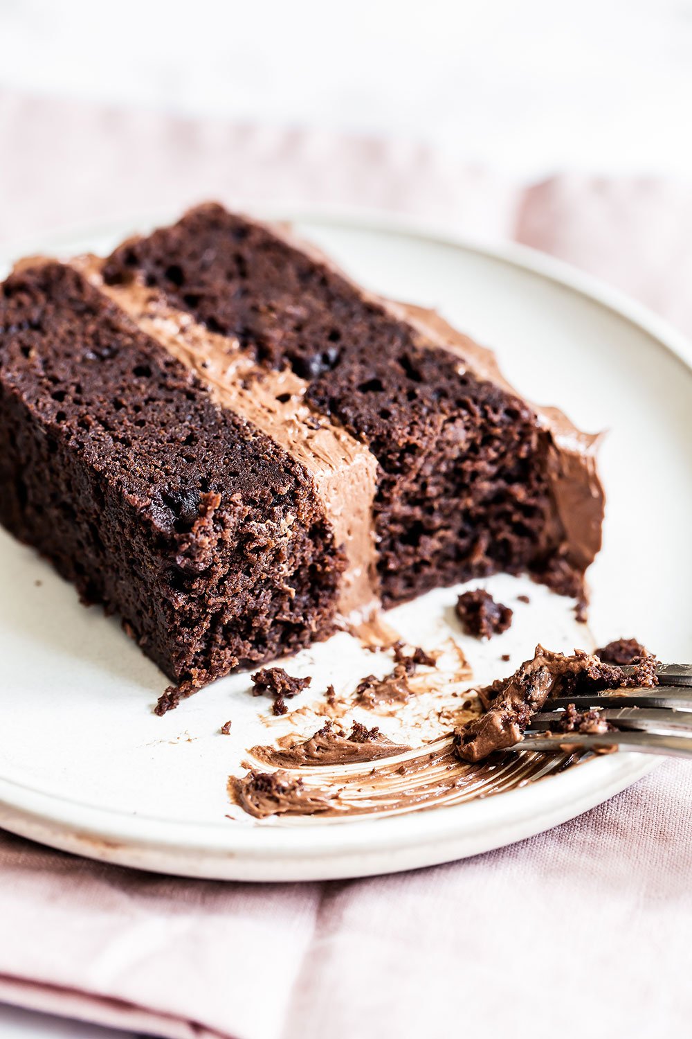 a slice of fudgy chocolate cake on a plate with a fork, ready to serve