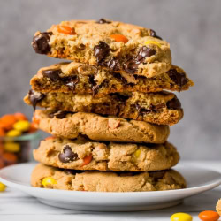 giant reese's pieces chocolate chip cookies stacked on a plate.