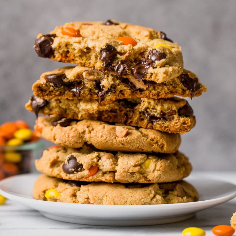 giant reese's pieces chocolate chip cookies stacked on a plate.