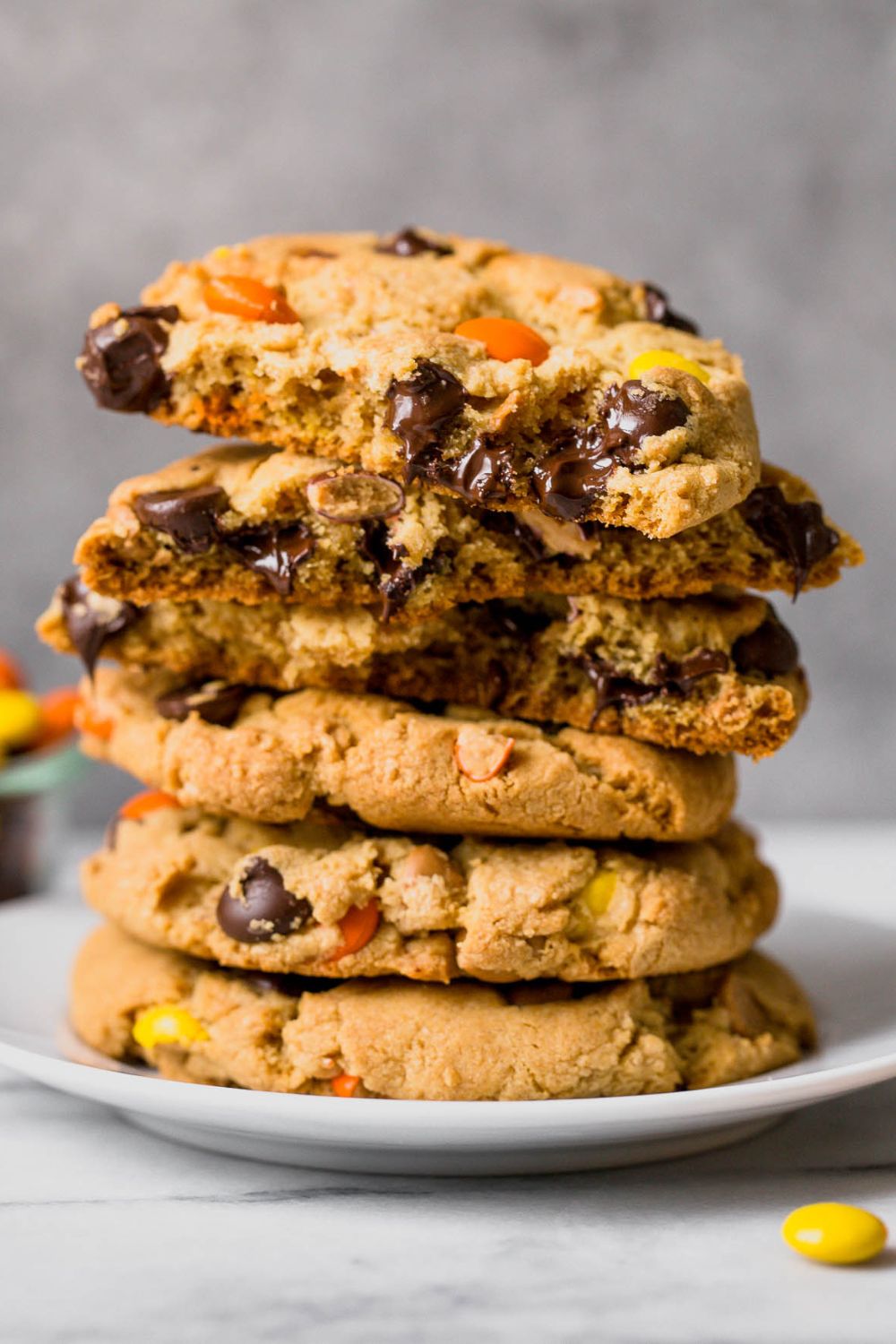 a stack of reese's pieces chocolate chip cookies on a plate.