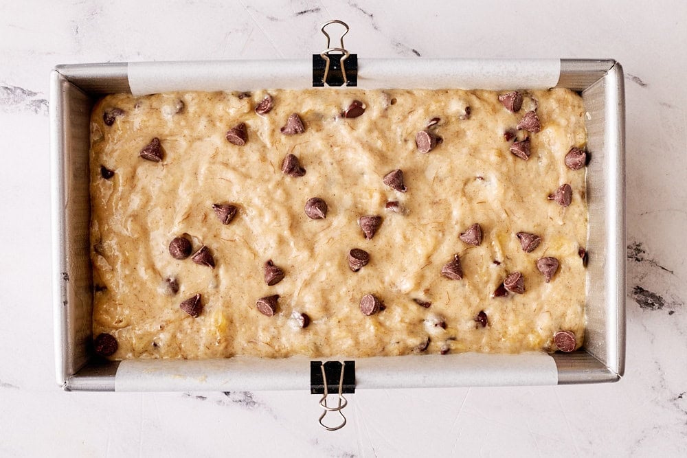 overhead view of banana bread batter in a metal pan lined with parchment paper