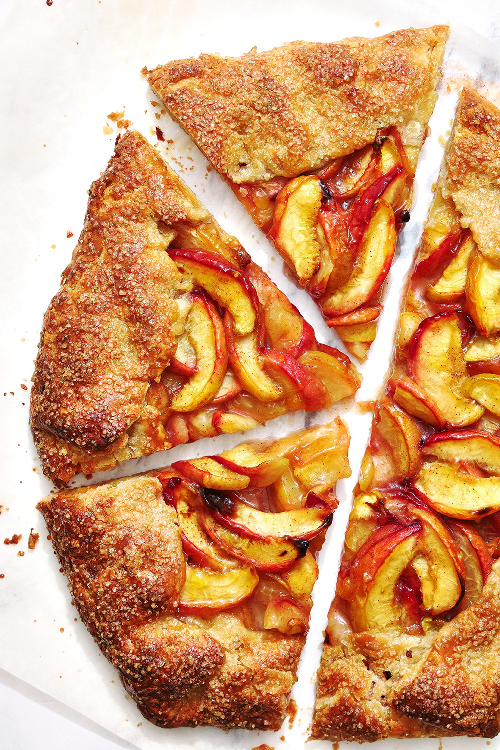 rustic peach galette recipe on parchment paper with 3 slices of galette cut out