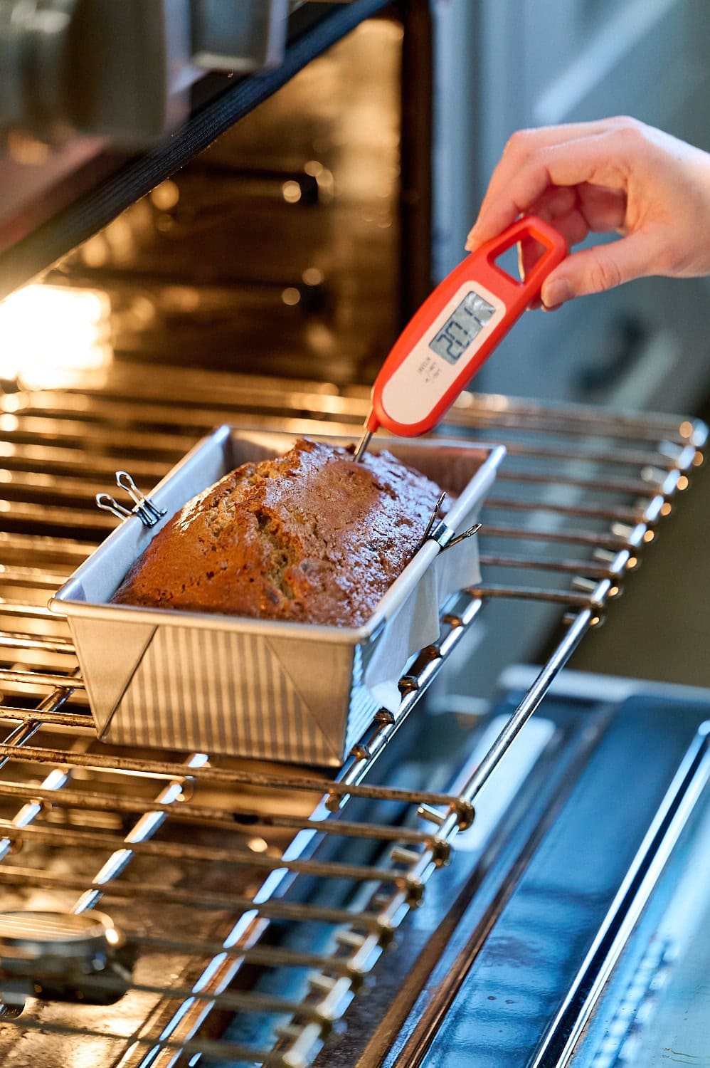 banana bread on oven rack with thermometer inserted to register temperature and doneness